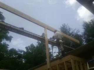 Carpenter setting a ridge beam over a new addition frame — Ice Dam Removal by Roofing Brothers in Nelliston