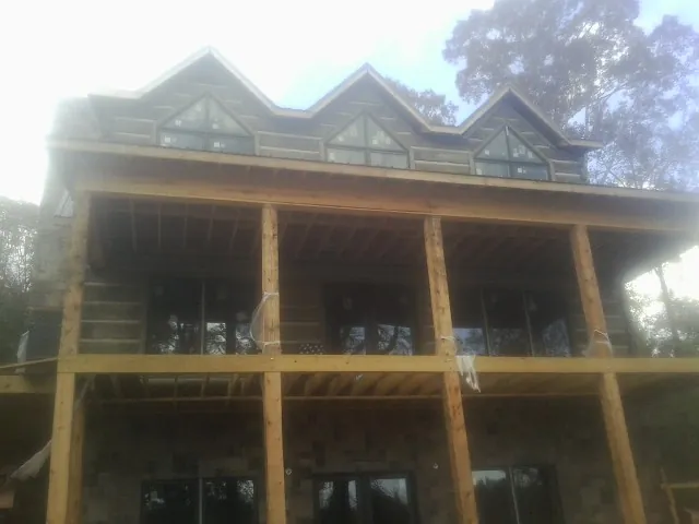 Dormers and porch framing on a large log home under construction — Roof Coating work by our crew in Nelliston