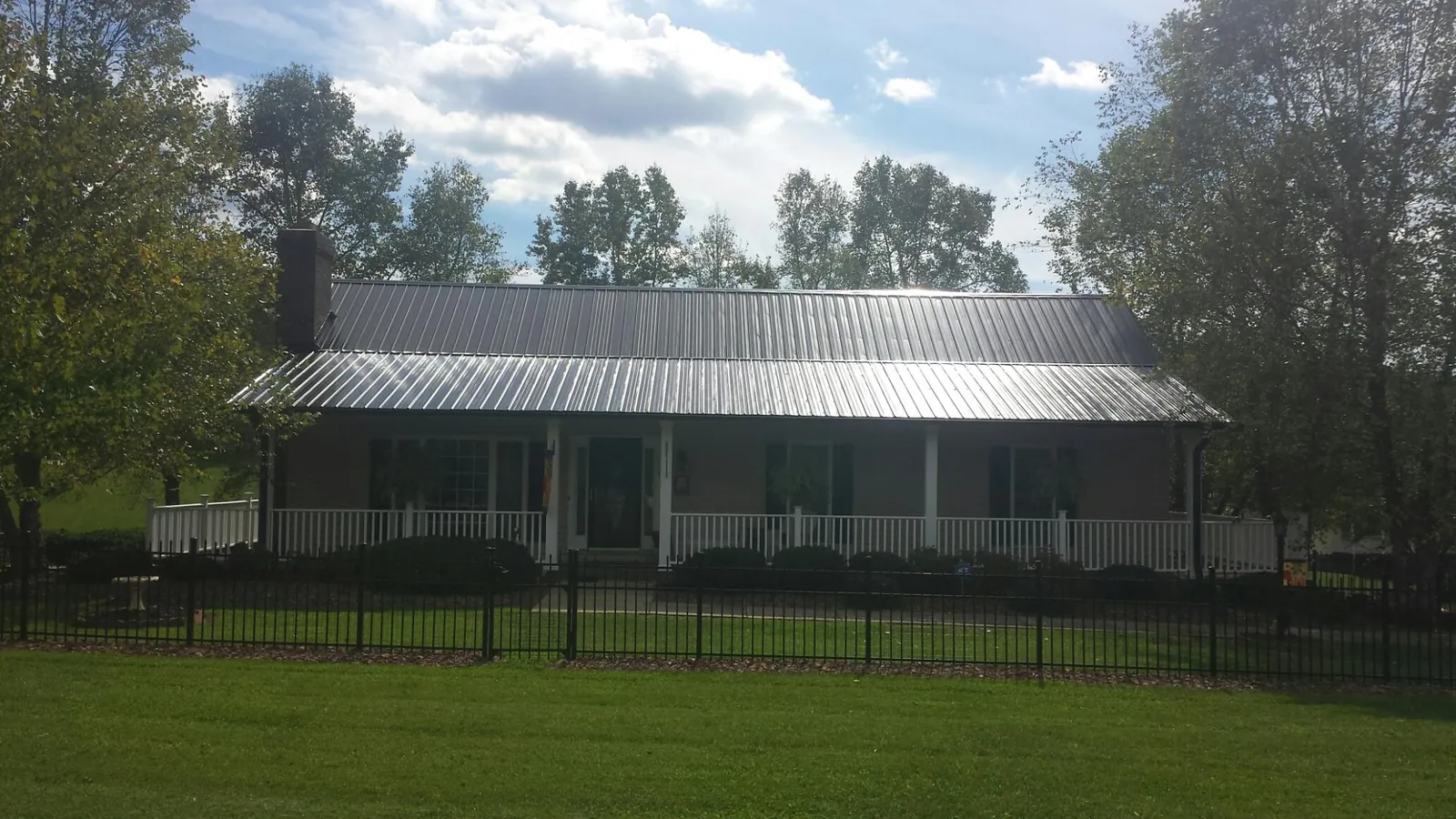Gray metal roof on a brick ranch with a full width front porch — Gutter Guard Installation work by our crew in Nelliston