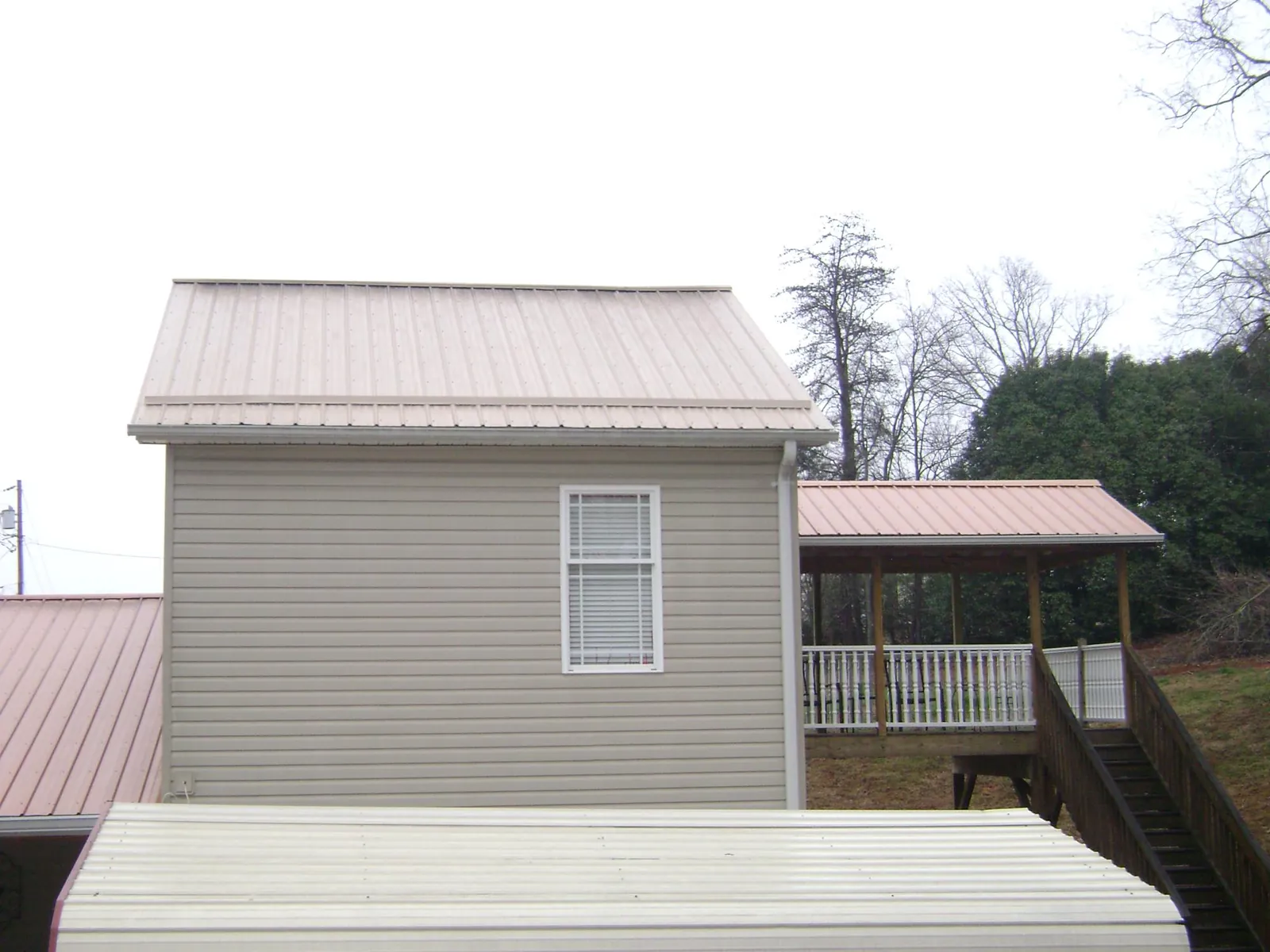 Tan metal roofs on a two story addition and attached porch, from a Roof Replacement job in Nelliston
